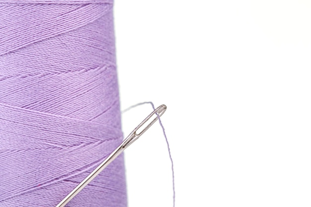 Macro skein of thread purple colors with a needle on a white background