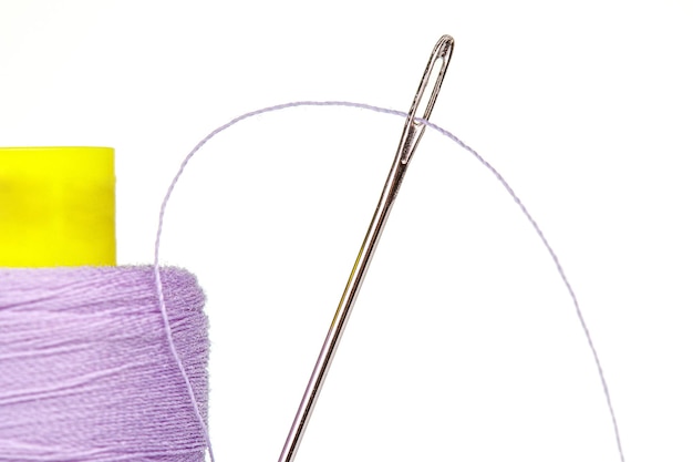 Macro skein of thread purple colors with a needle on a white background