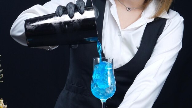 Photo macro of a skilled bartender hand pouring a blue hawaii in glass comestible