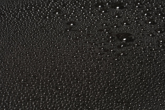 Macro of water drops with reflections on a glossy black surface