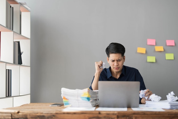 Mad crazy man employee sitting in office workplace with sticky notes all around shouting furious angry pissed off deadline and stressful job at office