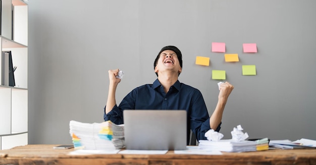 Mad crazy man employee sitting in office workplace with sticky notes all around shouting furious angry pissed off deadline and stressful job at office