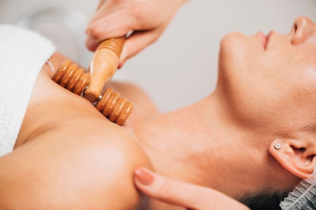 Maderotherapy AntiAging Massage Treatment of Woman's Decolletage and Neck with Wooden Roller