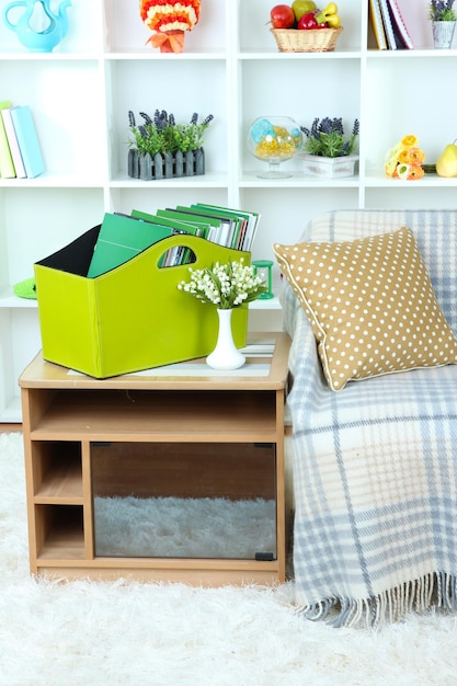 Magazines and folders in green box on bedside table in room