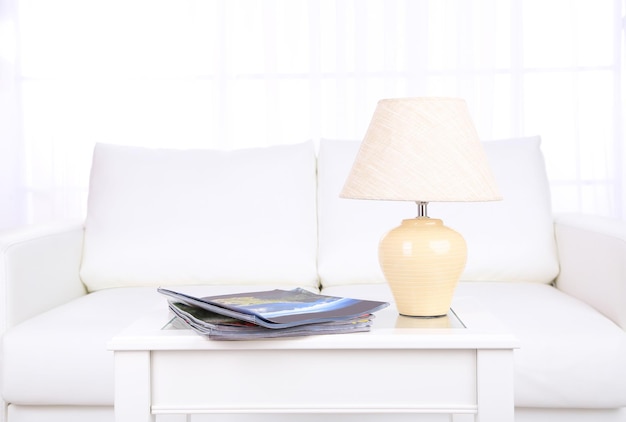 Magazines and lamp on coffee table in room