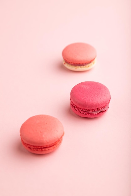 Magenta and pink macaroons on pink pastel background side view close up