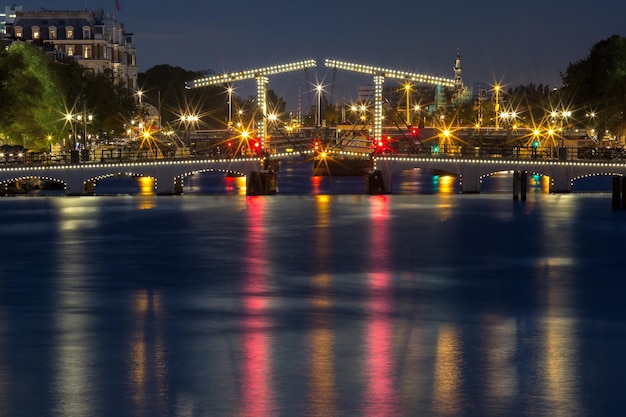 Magere brug skinny bridge with night lighting over the river amstel in the city centre of amsterdam