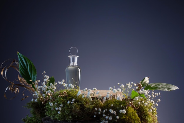 Magic potion in glass bottle with plants and flowers on blue background