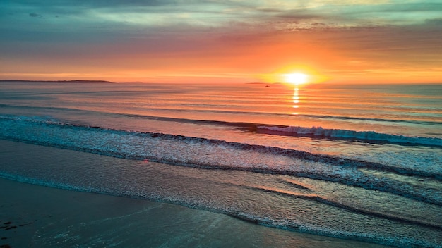 Magical sunrise aerial over beach with ocean waves in Maine