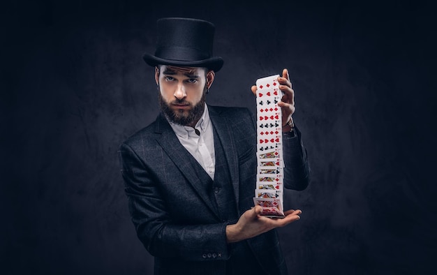 Magician showing trick with playing cards on a dark background.