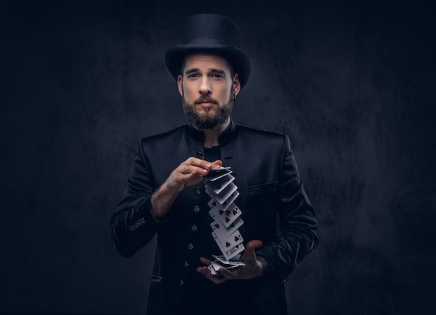 Magician showing trick with playing cards on a dark background.