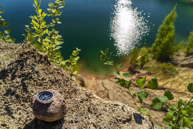 The magnetic compass lies on a stone at the edge of the reservoir