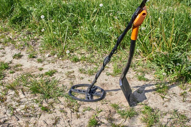 Magnetic metal detector and shovel for searching for precious metals and coins against the background of a path in a field