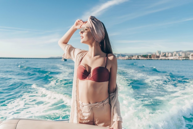 A magnificent beautiful woman enjoys sea voyage and vacation on her yacht in the sun