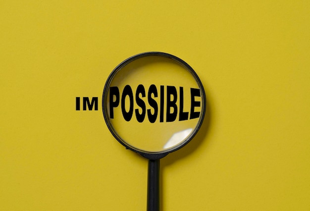 Magnifier glass focusing to possible from impossible wording on yellow background Positive thinking mindset and human inspiration development concept