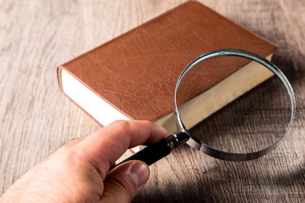 magnifying glass and book on the wooden background