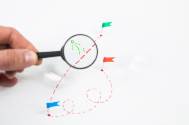 Under a magnifying glass, consider a route with a painted little man with flags on a white background