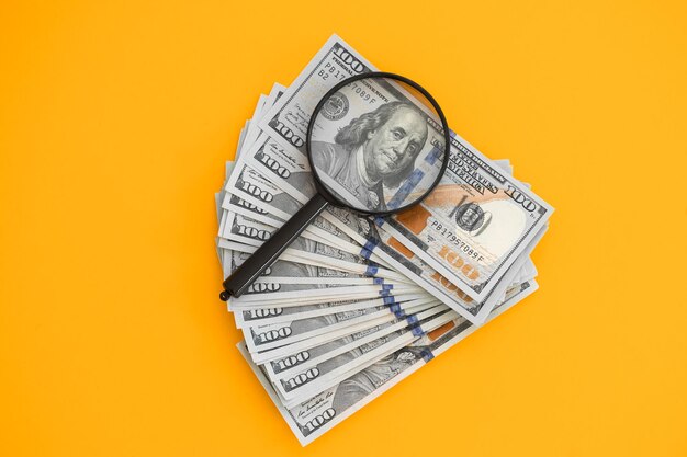 Magnifying glass on dollars on yellow background Economic and financial problems