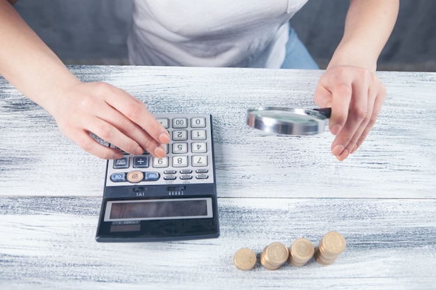 Photo a magnifying glass examines money and calculates on a calculator