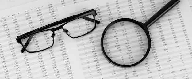 Magnifying glass and eye glasses on financial statement