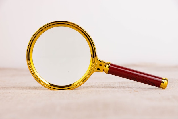 Magnifying glass of gold color on a light background and linen fabric. A copy of the space.