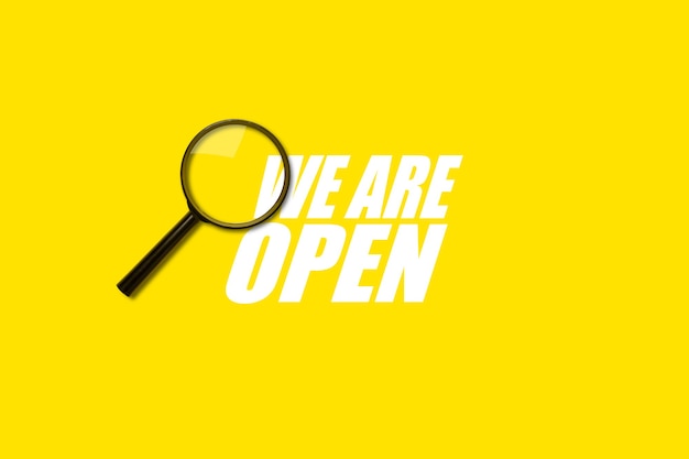 Magnifying glass loupe search on yellow surface. Added inscription We are open.