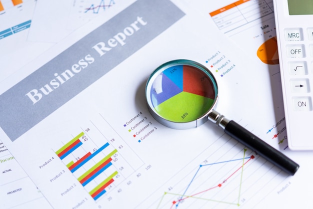 Magnifying glass on pie chart with statistics accounting info which including of many economic statistics business.