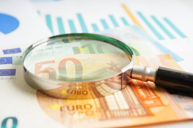 Magnifying glass on US dollar and EURO banknotes and graph finance business trade concept