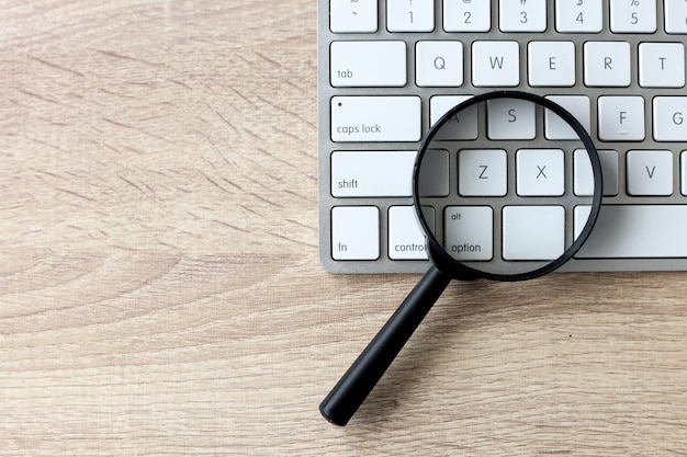 Photo magnifying glass on a white keyboard web search and seo concept