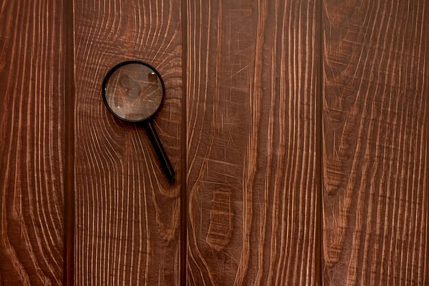 Magnifying glass on a wooden brown background. View from above. Research and Science.