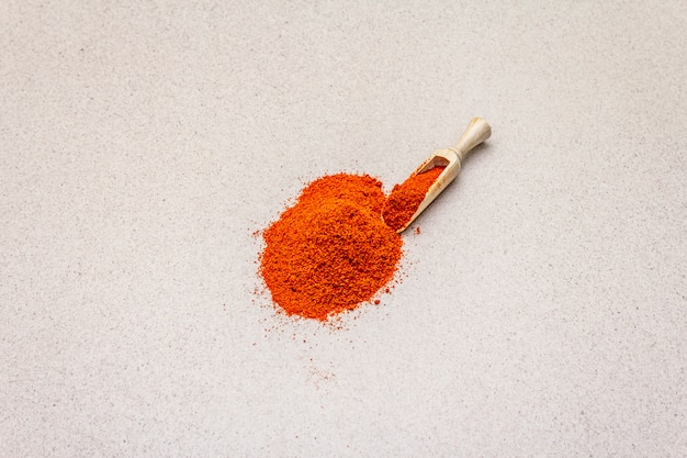 Magyar brilliant red sweet paprika powder. Traditional ingredient for cooking healthy food. Wooden scoop, stone concrete 