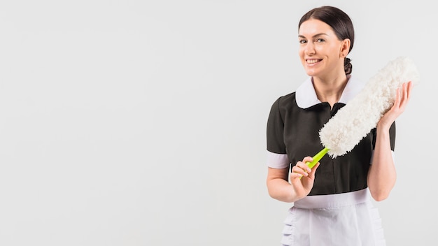 Maid in uniform smiling with duster 