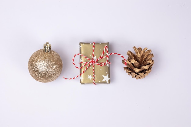 Main traditional christmas objects in golden colr ball gift box and golden pine cone on white backgr