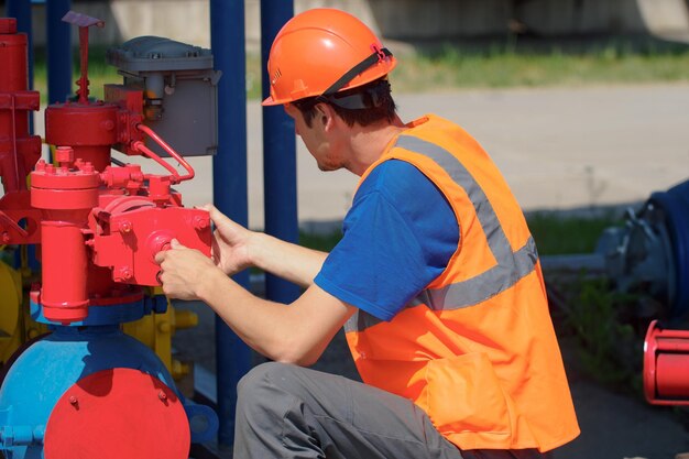 Maintenance of industrial gas equipment working man in hard hat checks equipment in warehouse on summer day