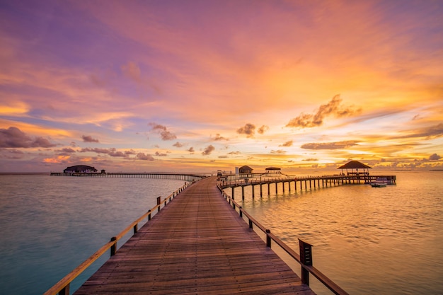 Majestic beach landscape. Beautiful Maldives sunset seascape. Pier villas colorful sea sky clouds