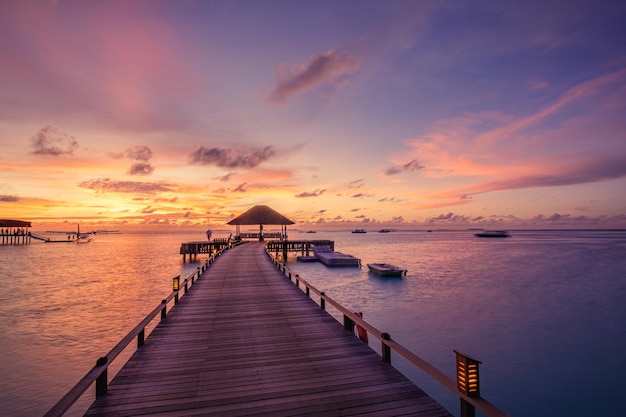 Majestic beach landscape. Beautiful Maldives sunset seascape. Pier villas colorful sea sky clouds