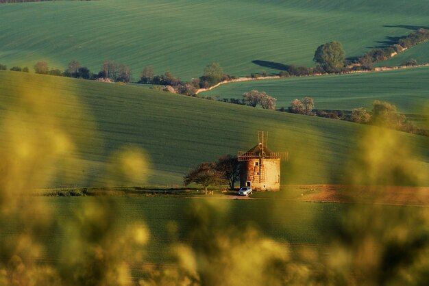 Majestic landscape of field in the evening. Windmill in the center of meadow.