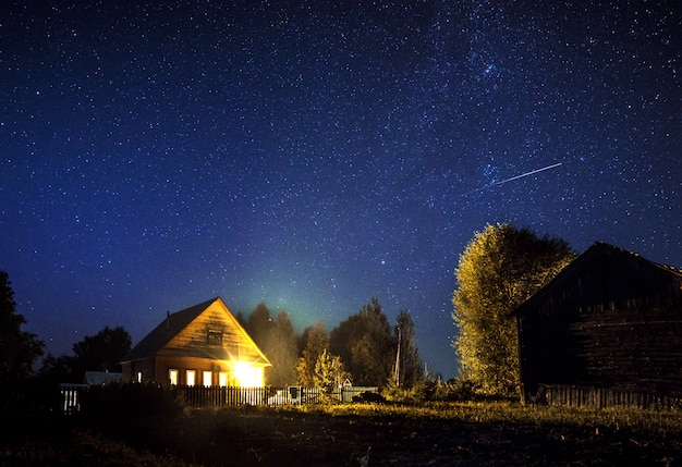 Majestic milky Way and the shooting star above the village house in summer. A starry night sky.