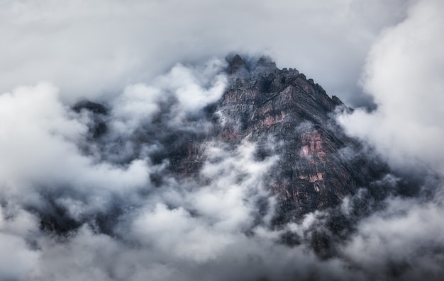 Majestical scene with mountains in clouds in overcast evening