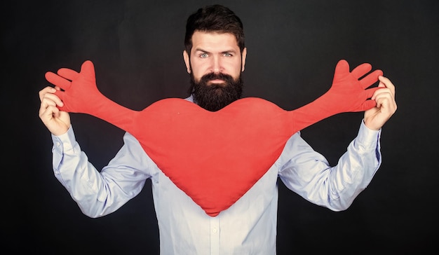 Photo make him feel loved every day man bearded hipster hug heart celebrate valentines day guy with beard and mustache in love romantic mood feeling love dating and relations concept happy in love