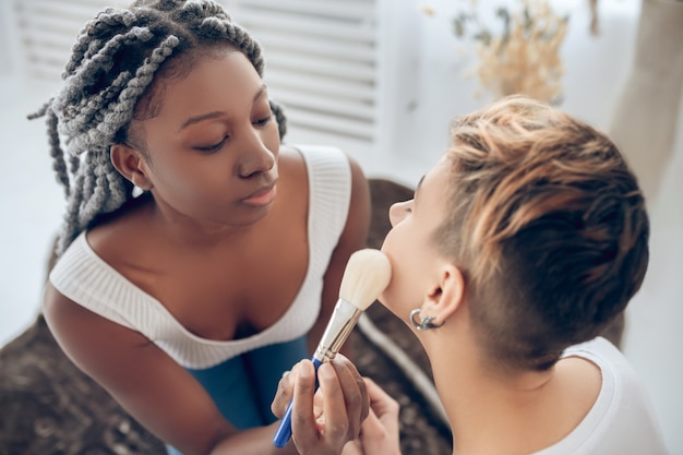 Make up. African american girl doing make up to her girlfriend