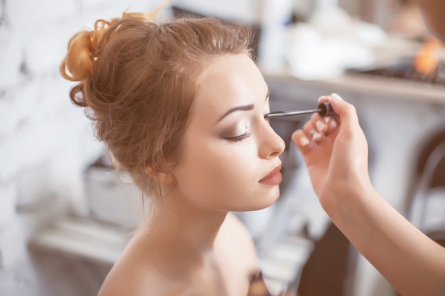 Make-up artist applying the mascara to model.