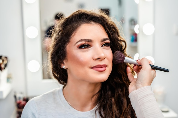 Make up artist applying professional make up to beautiful middle-aged woman.