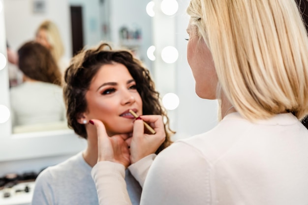 Make up artist applying professional make up to beautiful young woman.