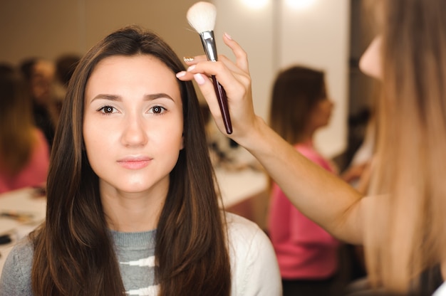 Make up artist doing professional make up of young woman. Beauty shcool.