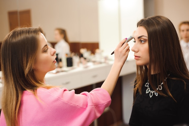 Make up artist doing professional make up of young woman.