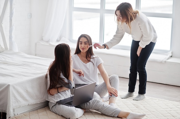 Make up artist prepare two twins models with laptop on studio before photoshoot.