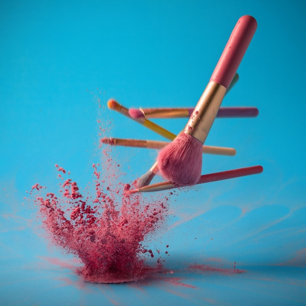 Make up brushes with powder splashes isolated on pink background