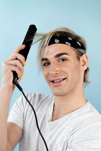 Make-up man using flat iron on his hair