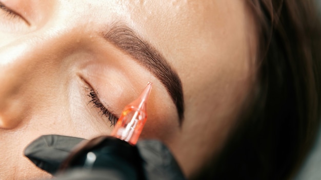 Make-up master performs the procedure of permanent eyebrow makeup for the client